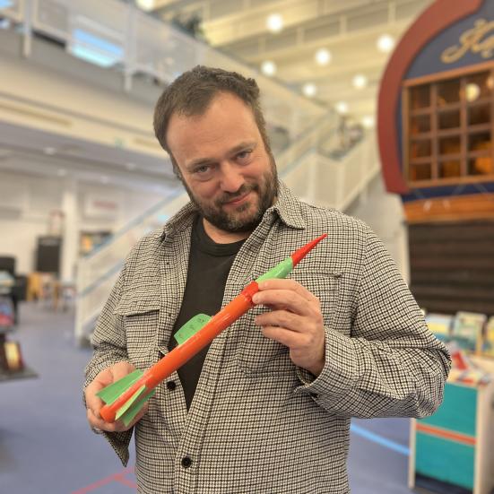 Børnebibliotekar Ulrik står med en lille hjemmelavet og ufarlig raket