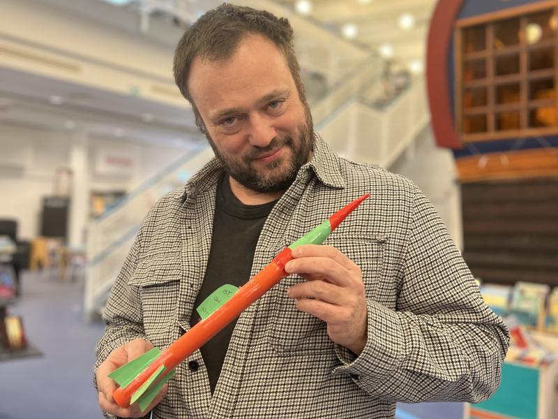 Børnebibliotekar Ulrik står med en lille hjemmelavet og ufarlig raket