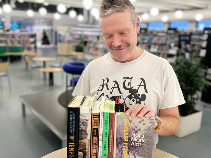 Litteraturformidler Thomas står med bøger, som han læste højt i til litterær vandring om Mørket