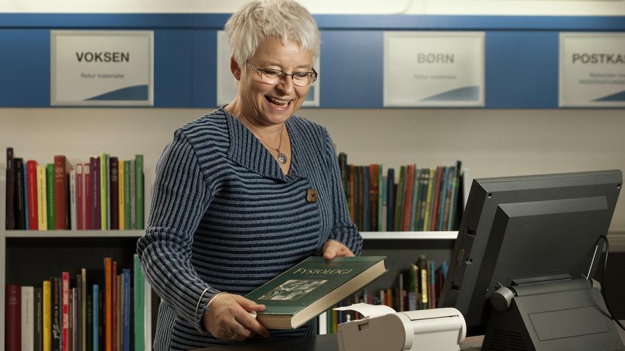 Kvinde afleverer bøger på bibliotekets selvbetjeningsmaskiner
